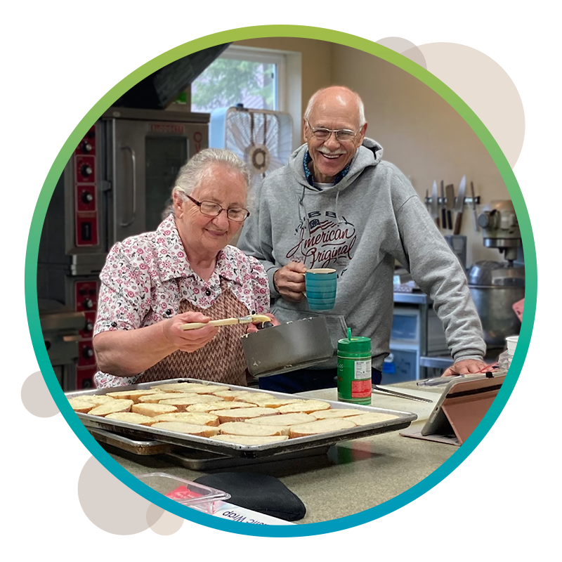 Two volunteer staff members baking cookies for the camp