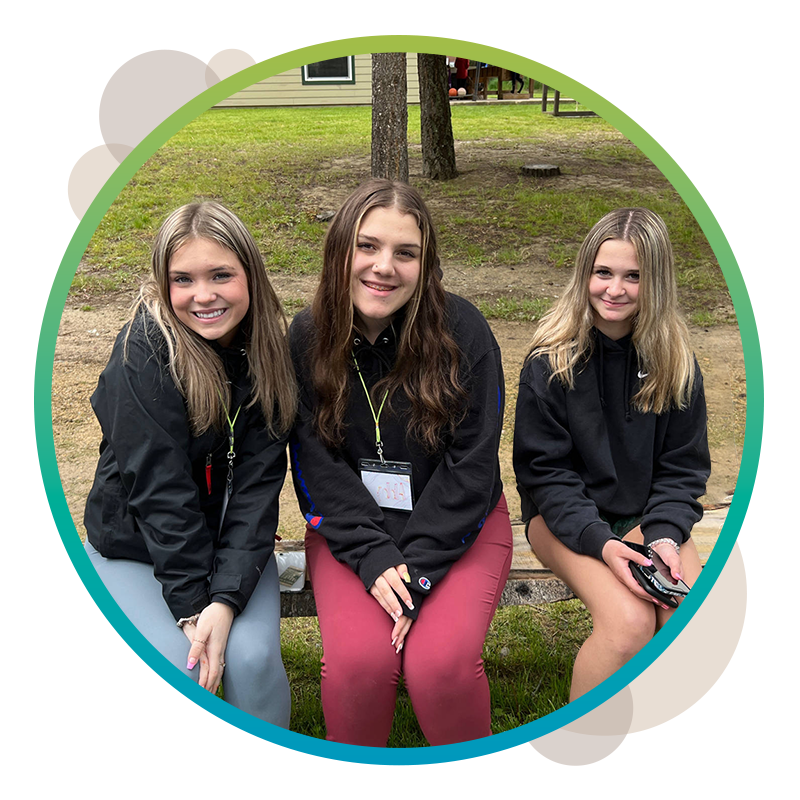 Three LC Unite for Youth camp attendees sitting together on a bench